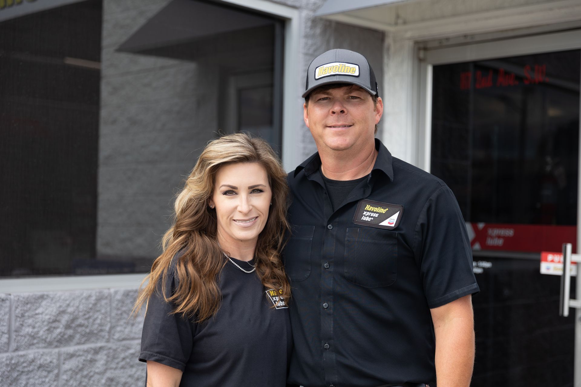 A man and a woman are posing for a picture in front of a building.