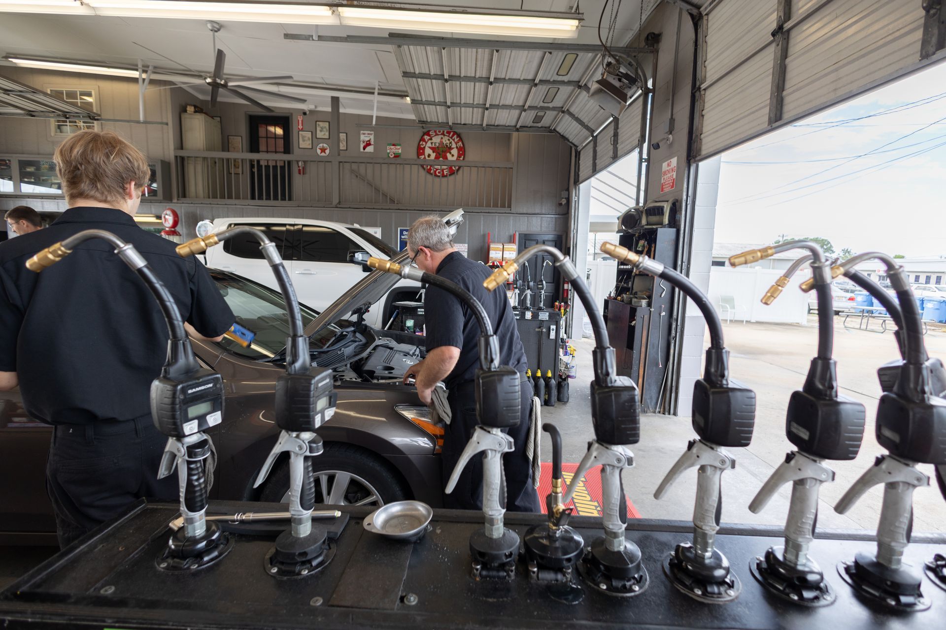 A group of men are working on a car in a garage.