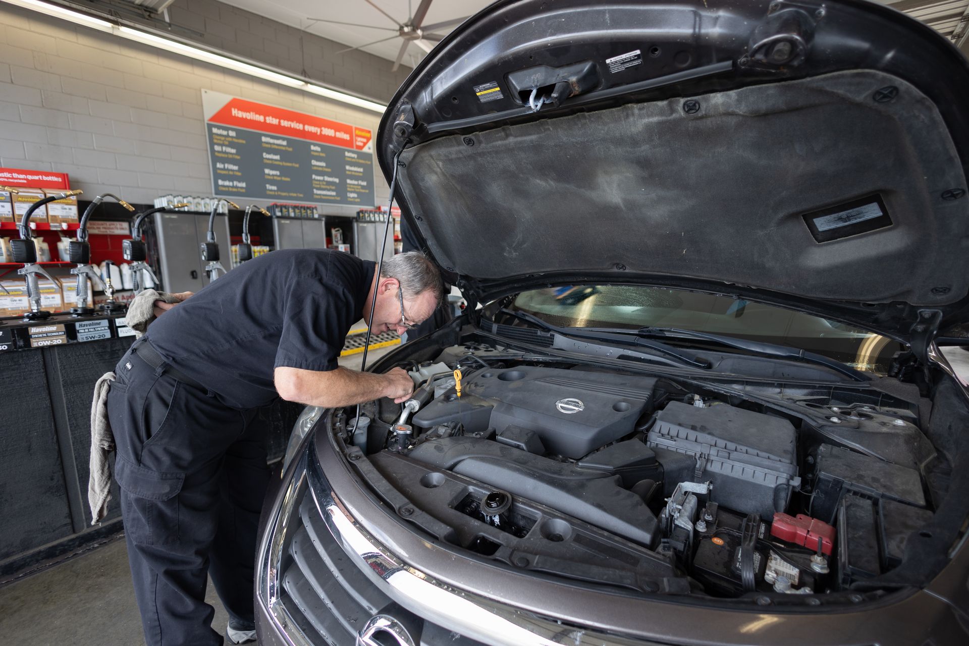 A man is working on the engine of a car in a garage.