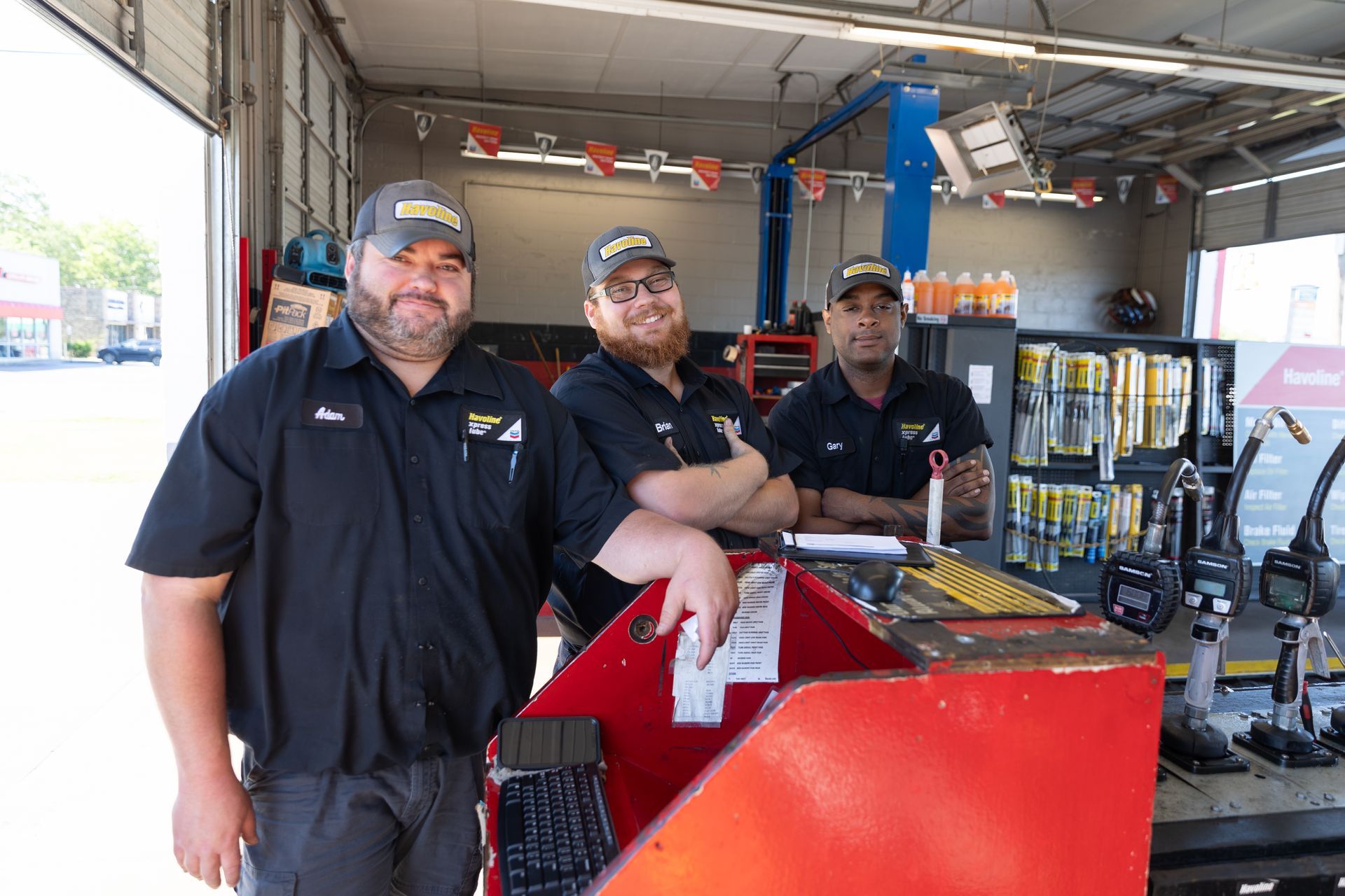 Three men are standing next to each other in a garage.