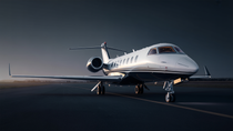 White private jet on a tarmac, ready for takeoff with a dusky sky backdrop.