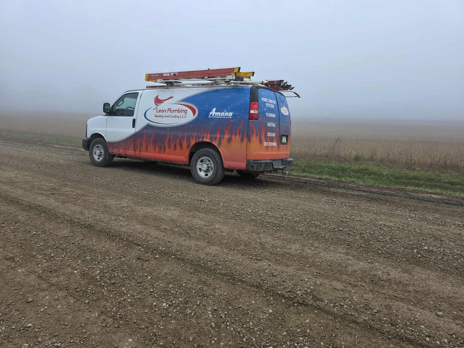 White van with company logo on a gravel road, obscured by fog.