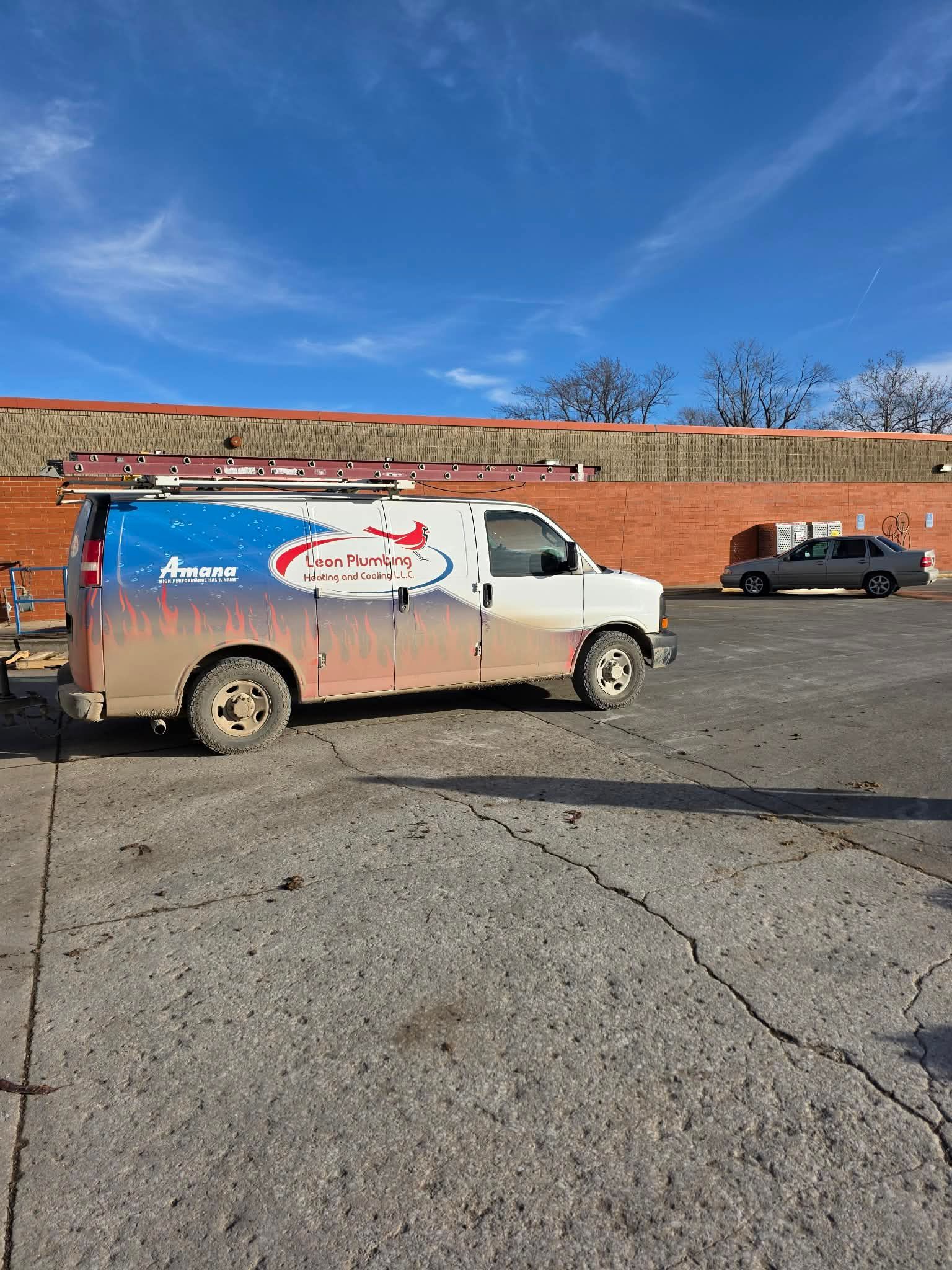 White work van with logo parked on cracked pavement, blue sky background.