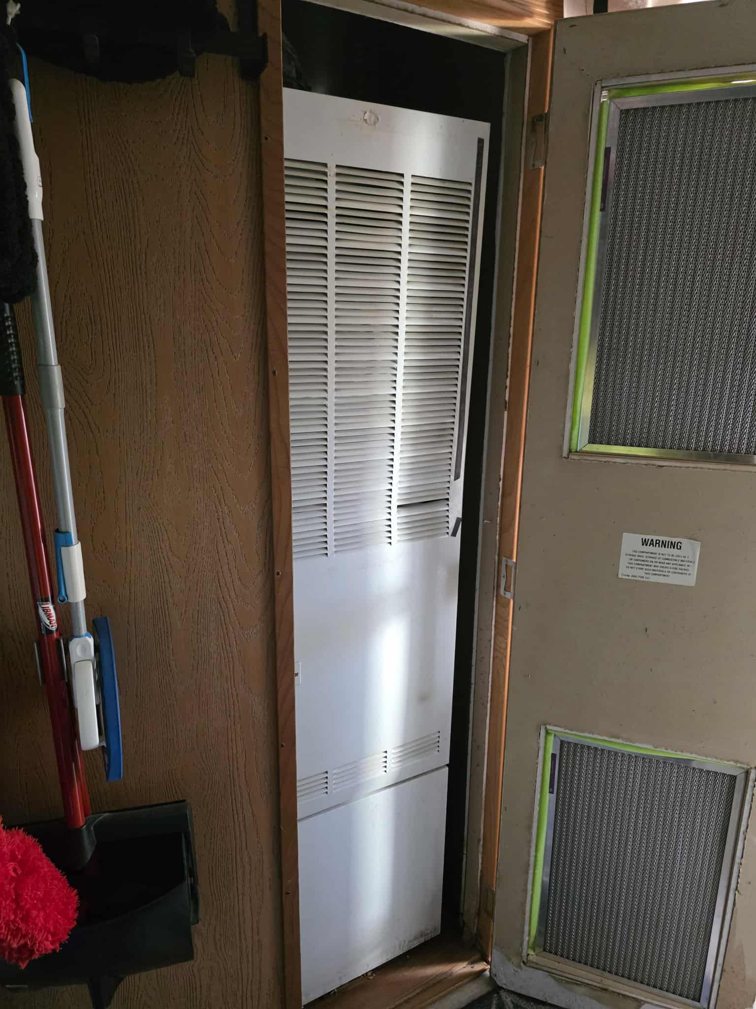 Open doorway with a white HVAC unit. Two screen vents are on the wall to the right. A mop is on the left.