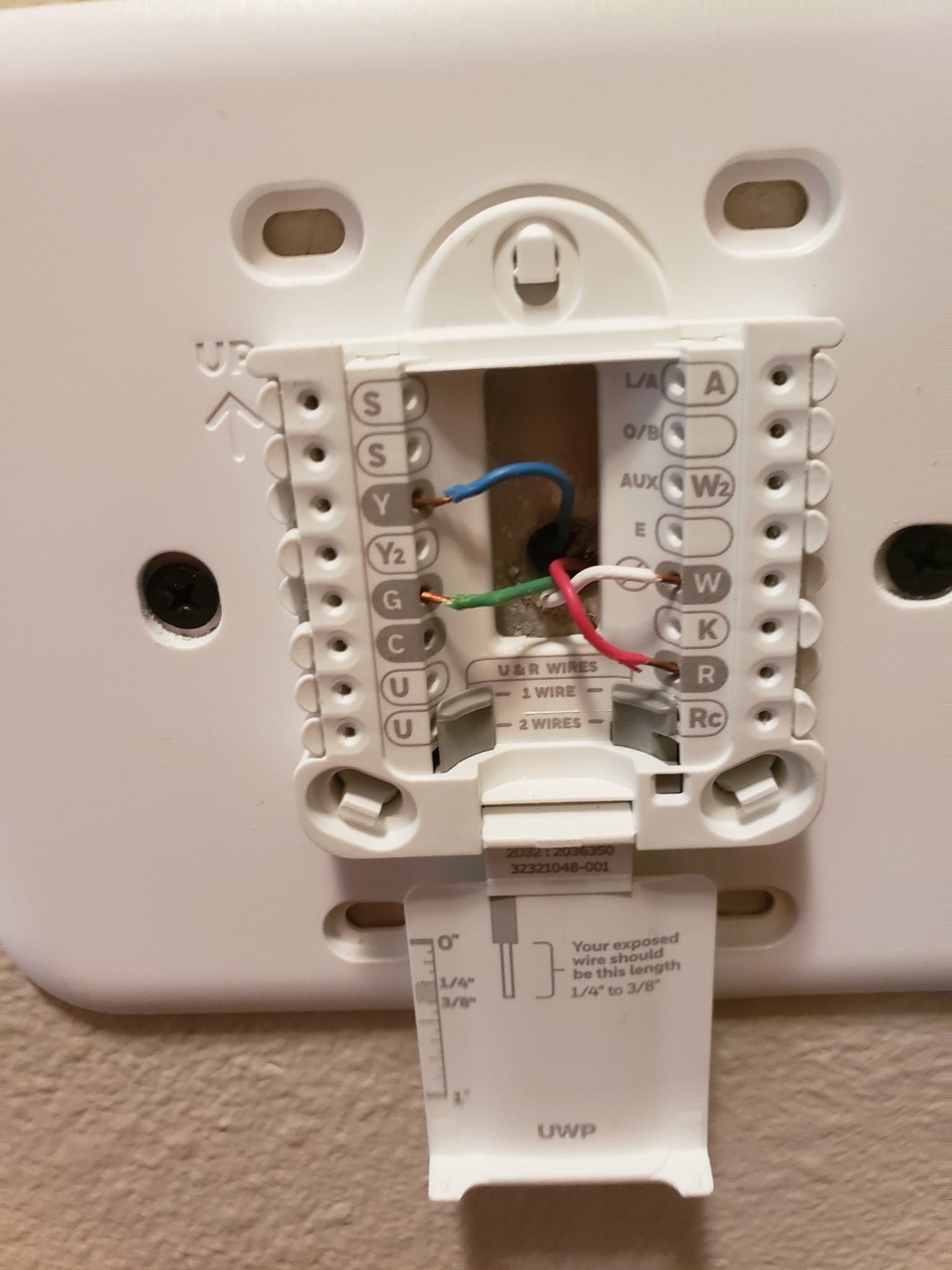 White thermostat base with colored wires connected to labeled terminals.