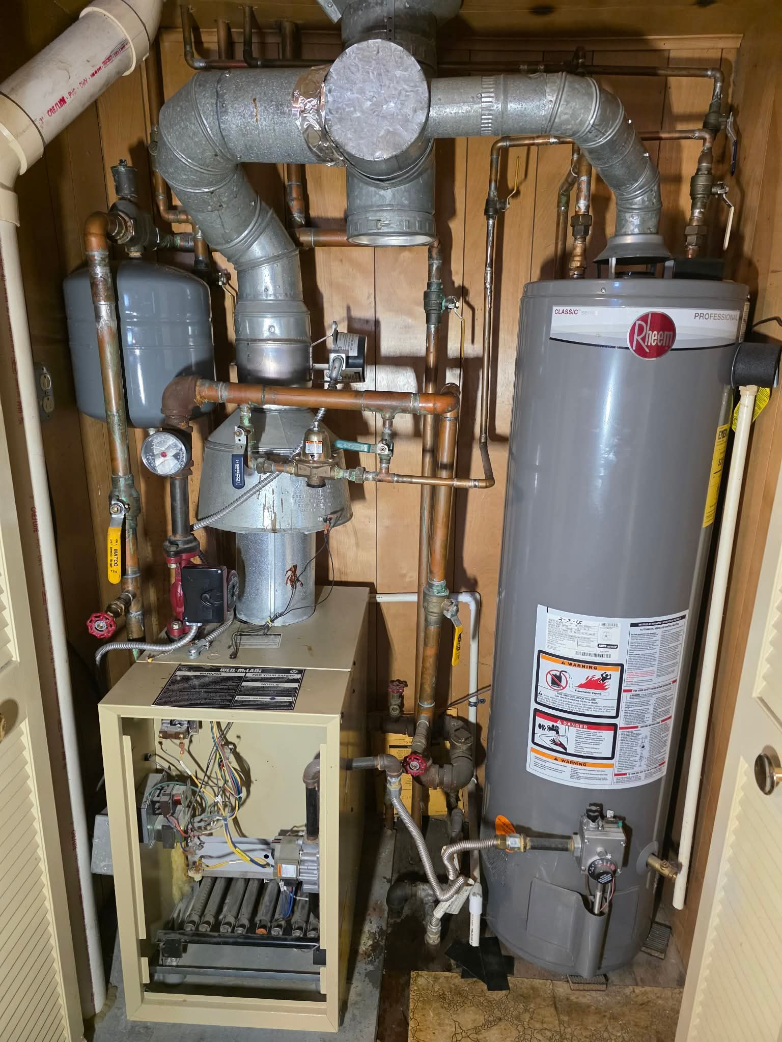 Furnace and water heater in a utility closet with associated pipes and venting.