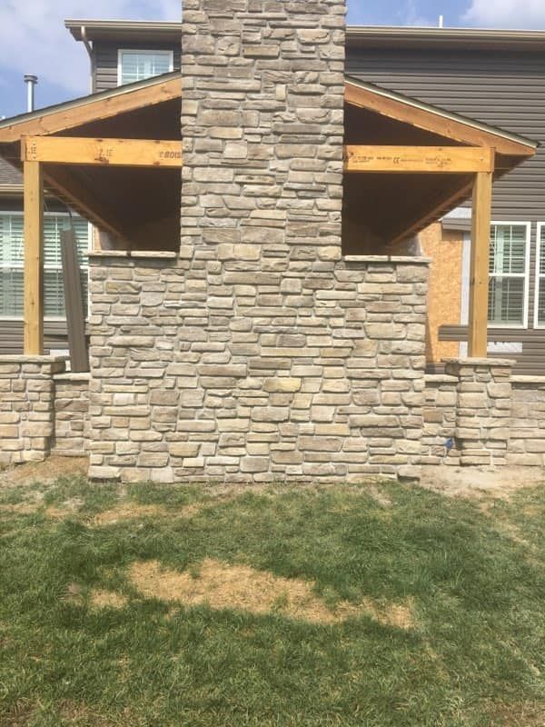 A large stone chimney is sitting in front of a house.