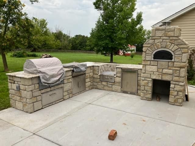 An outdoor kitchen with a grill and a pizza oven