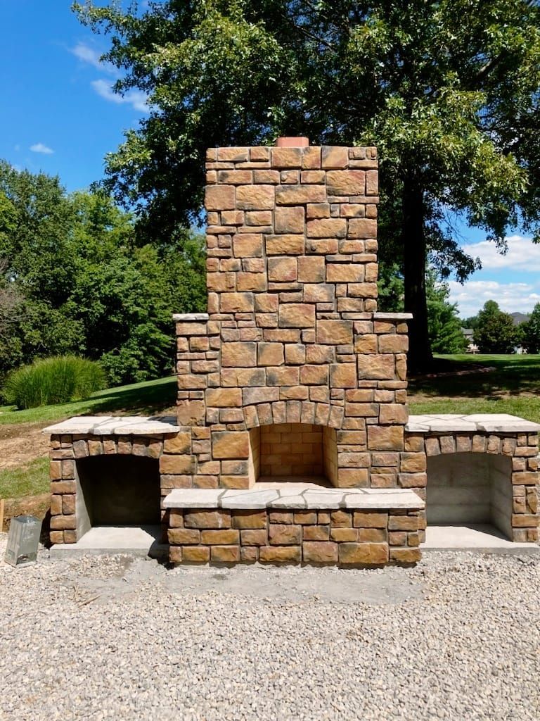 A large brick fireplace is sitting in the middle of a gravel driveway.