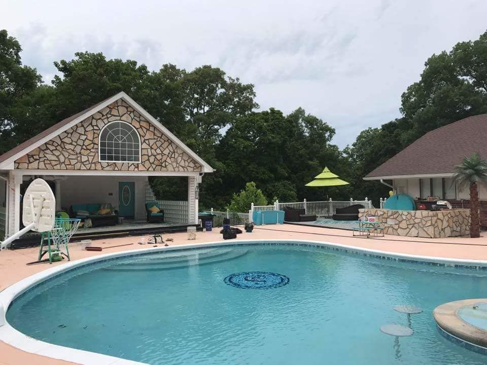A large swimming pool with a house in the background