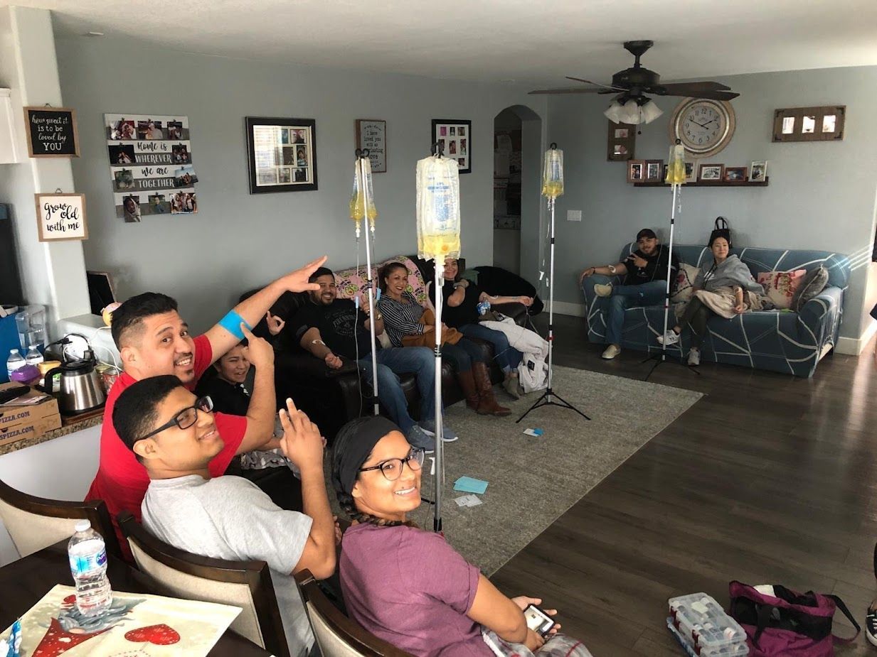 A group of people are sitting in a living room with iv drips in them.