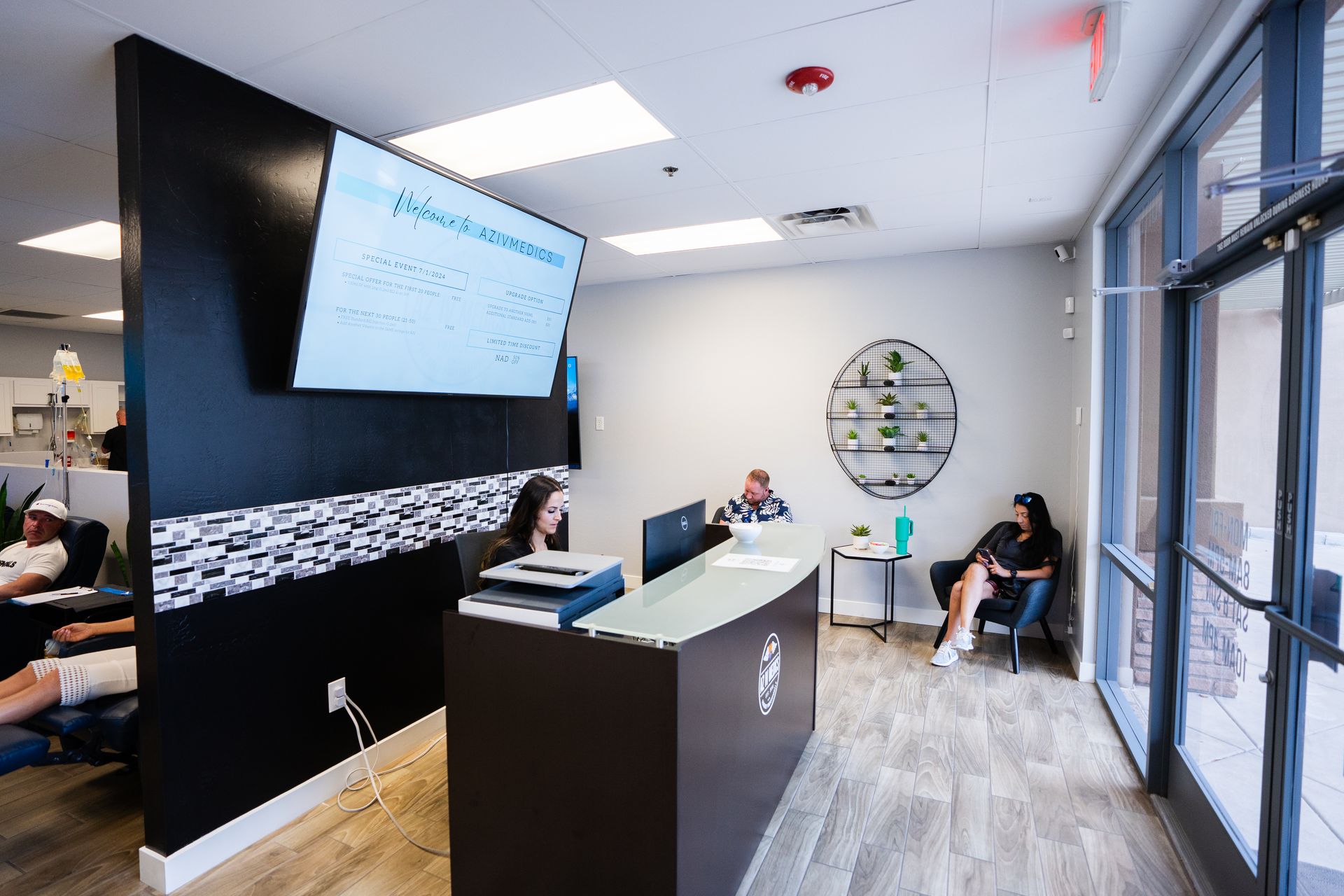 A group of people are sitting at a desk in a waiting room.