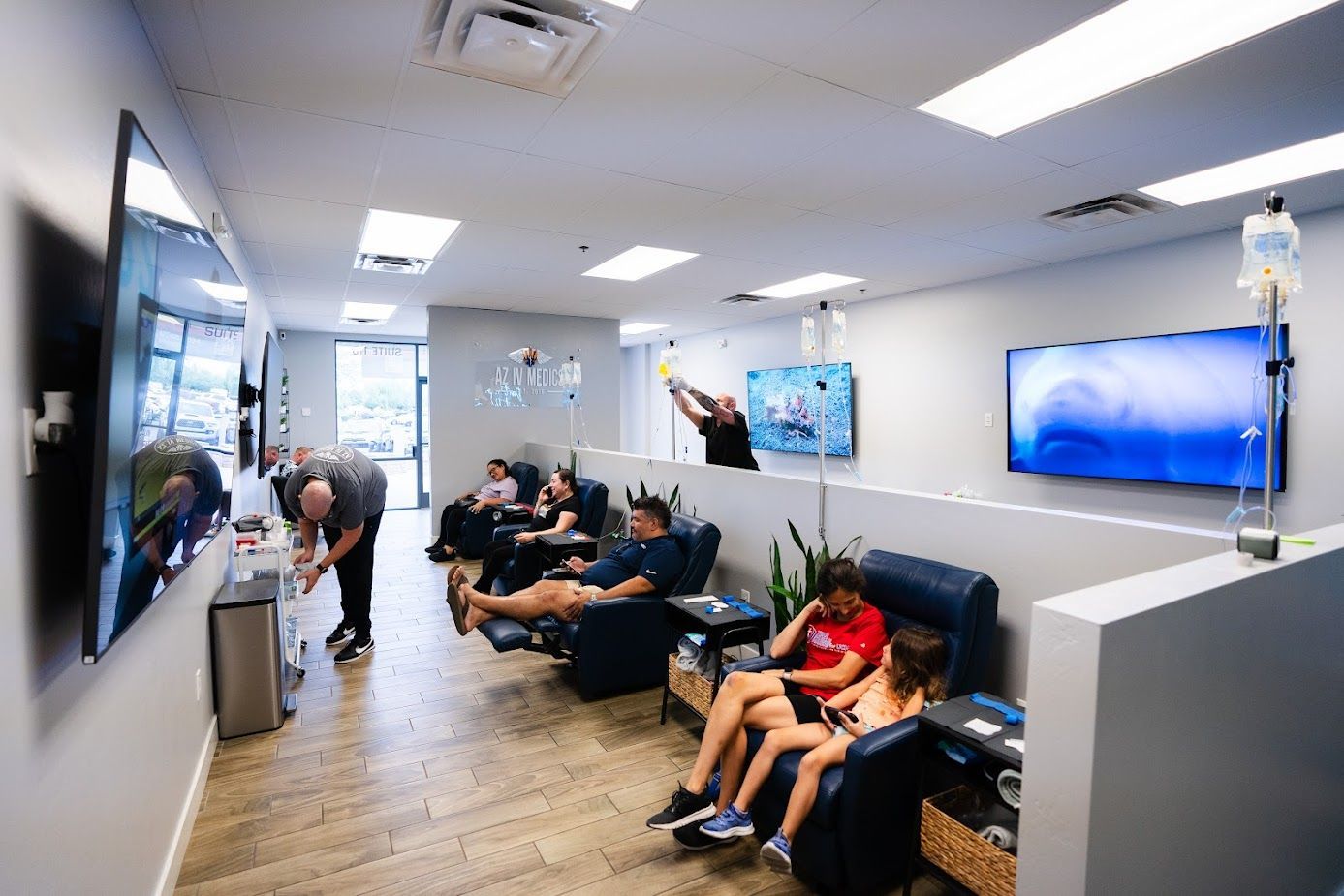 A group of people are sitting in chairs in a waiting room of AZ IV MEDICS clinic