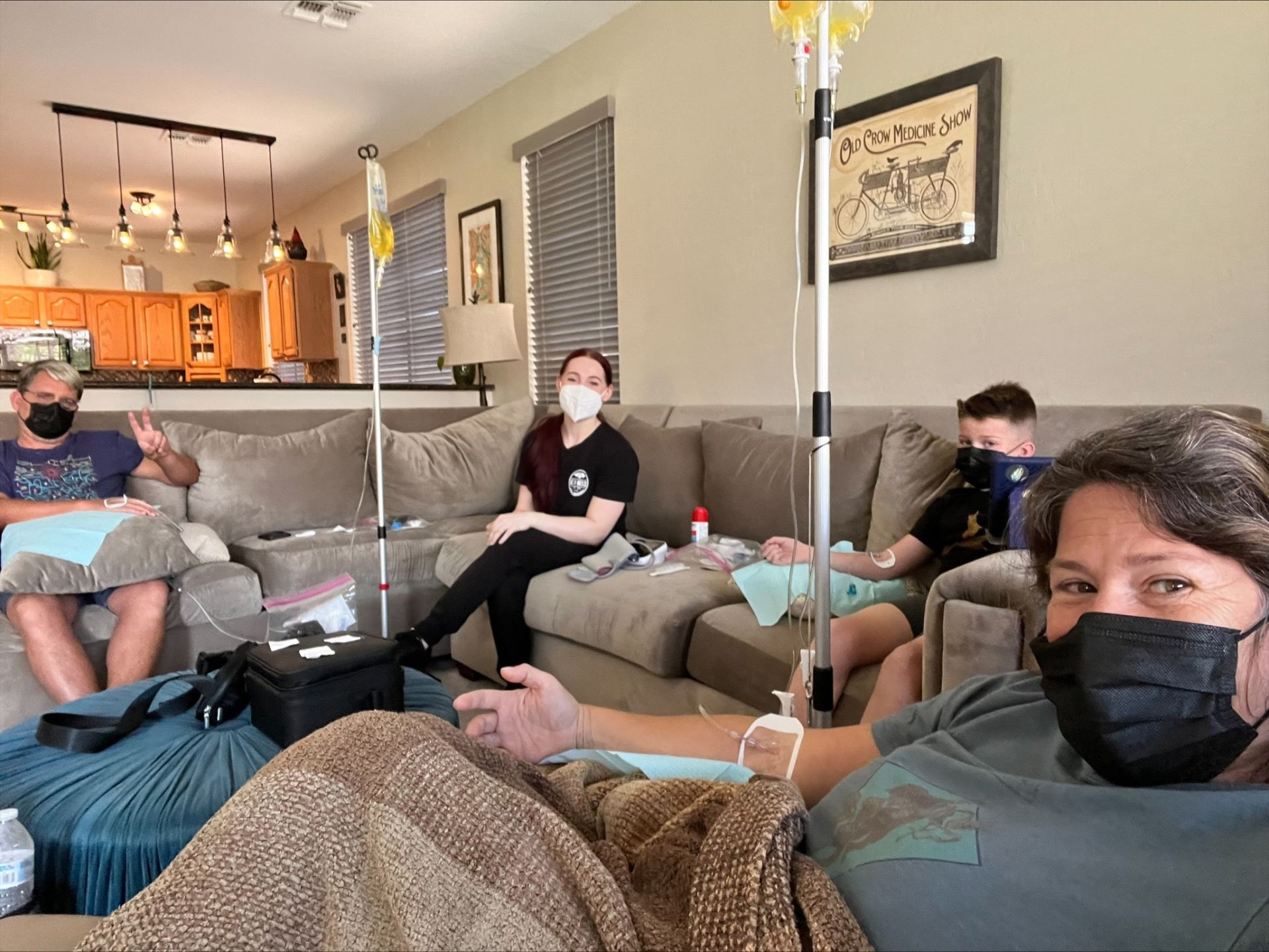A group of people wearing face masks are sitting on a couch.