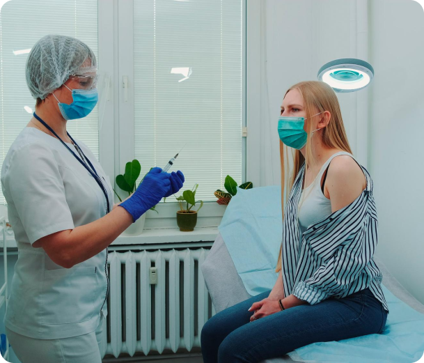 A woman wearing a mask is getting an injection from a nurse.