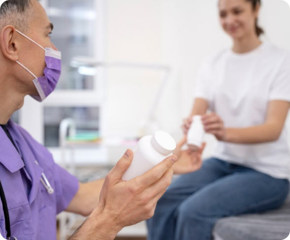 A doctor is talking to a patient while holding a bottle of pills.