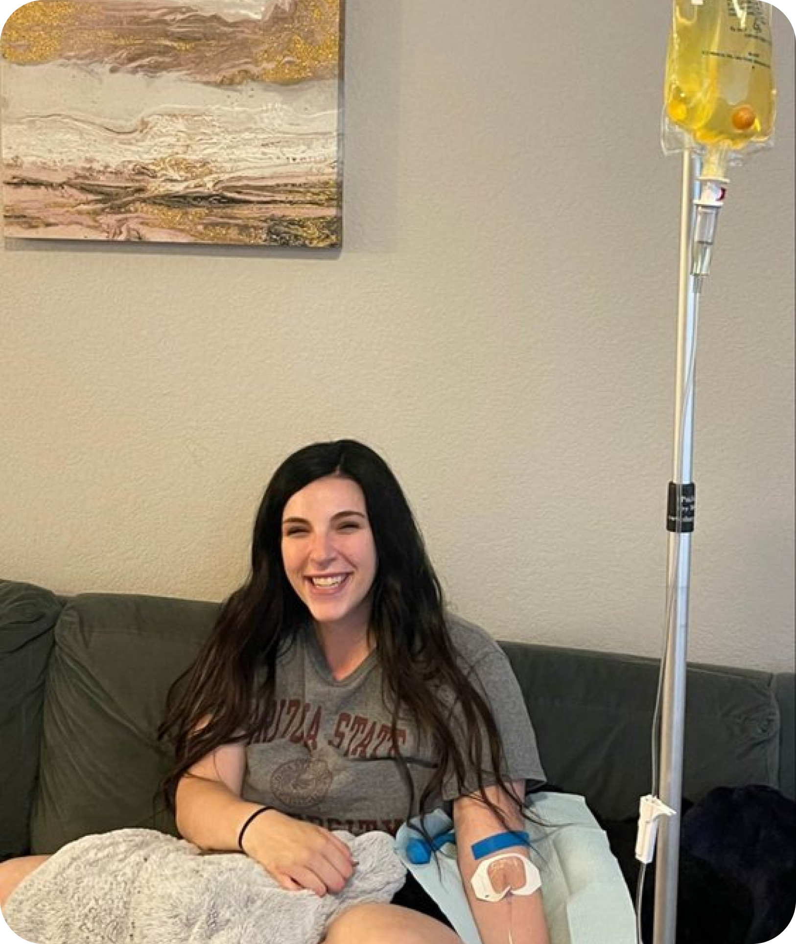A woman is sitting on a couch with an iv in her arm.