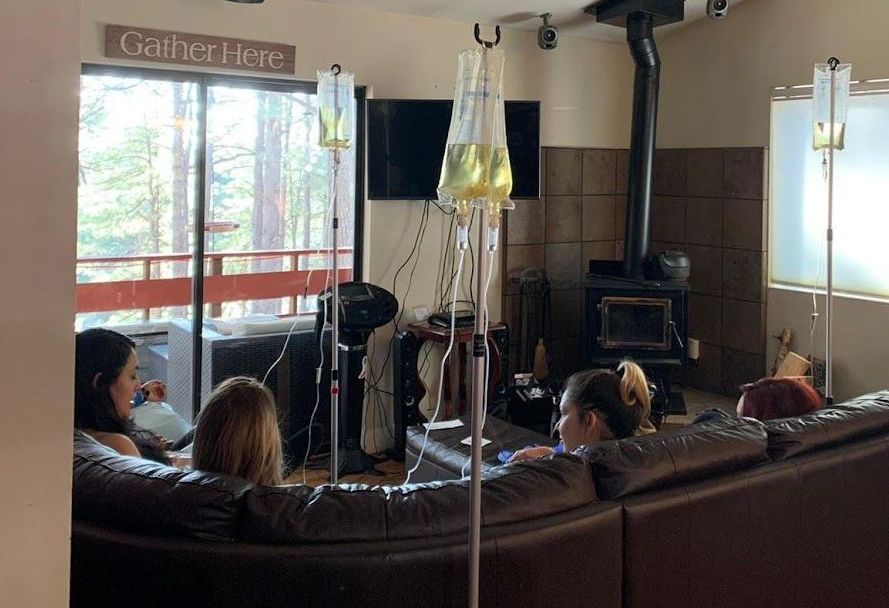 A group of people are sitting on a couch in a living room with IV