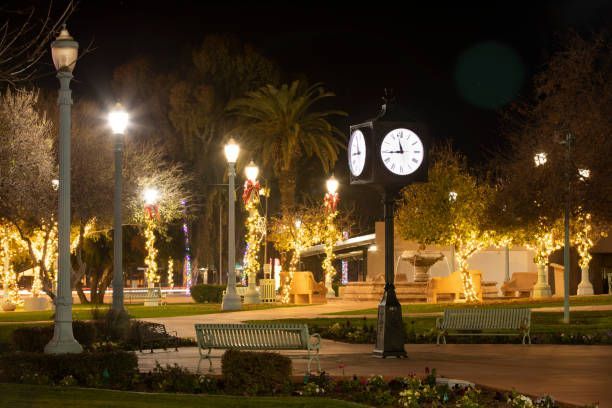 There is a clock in the middle of a park at night.