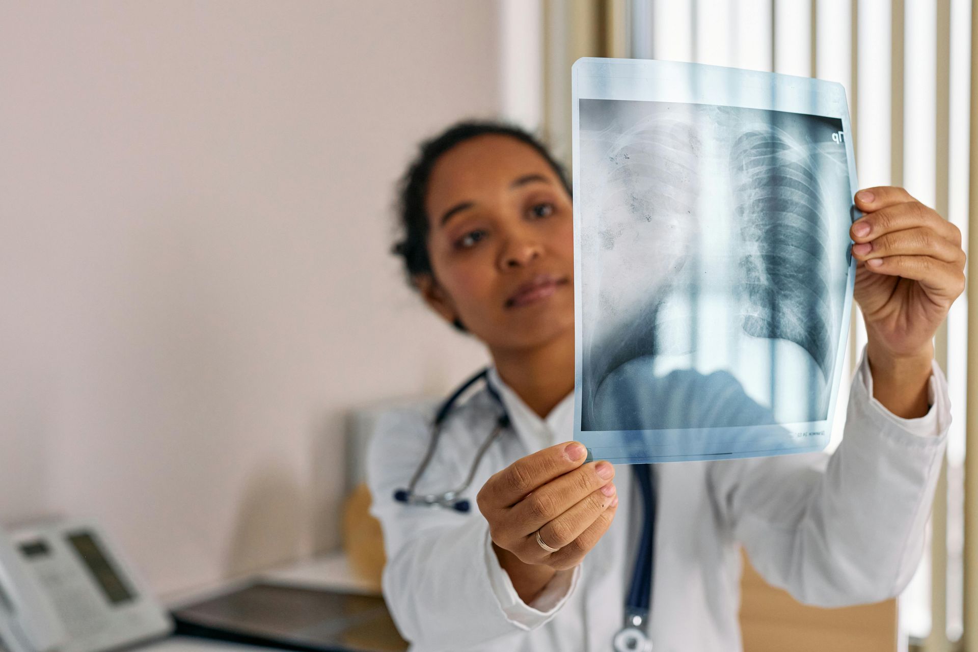 Doctor holding and examining an X-ray, looking at the results.