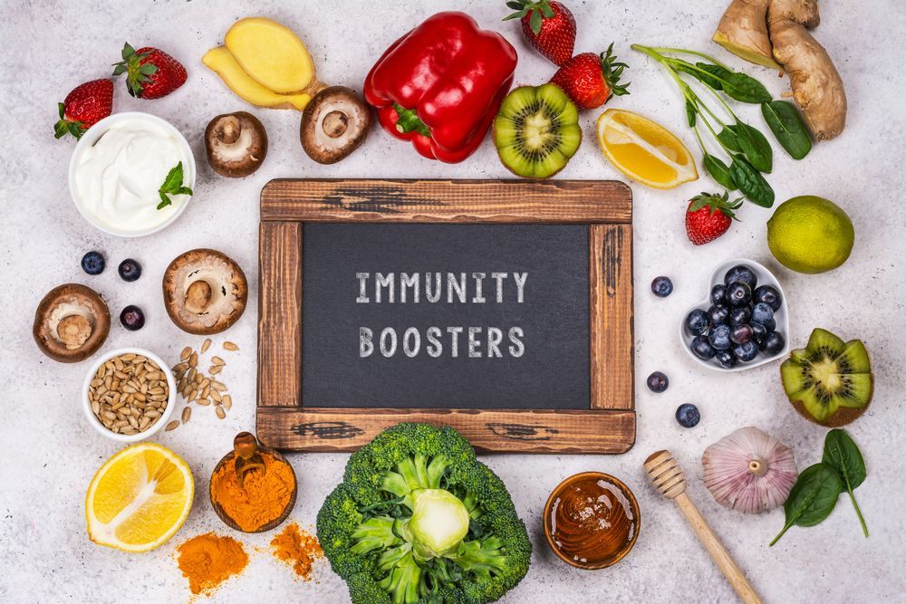 A chalkboard surrounded by fruits and vegetables with the words `` immunity boosters '' written on it.