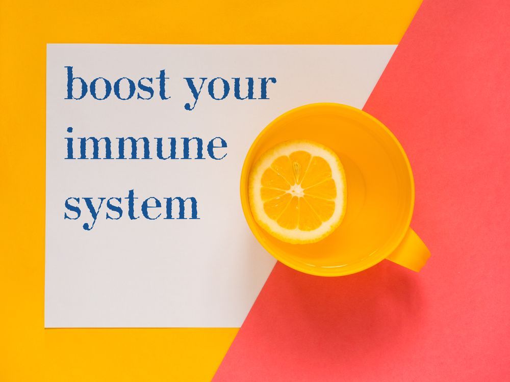 A yellow cup with a slice of lemon in it and a sign that says `` boost your immune system ''.