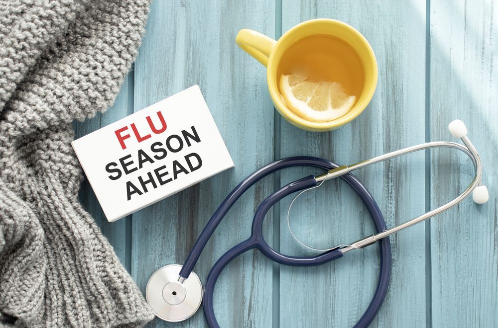 A sign that says `` flu season ahead '' next to a stethoscope and a cup of tea.