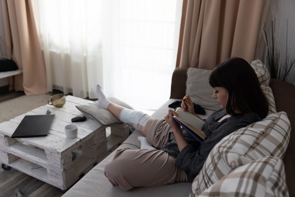 A woman is sitting on a couch reading a book.