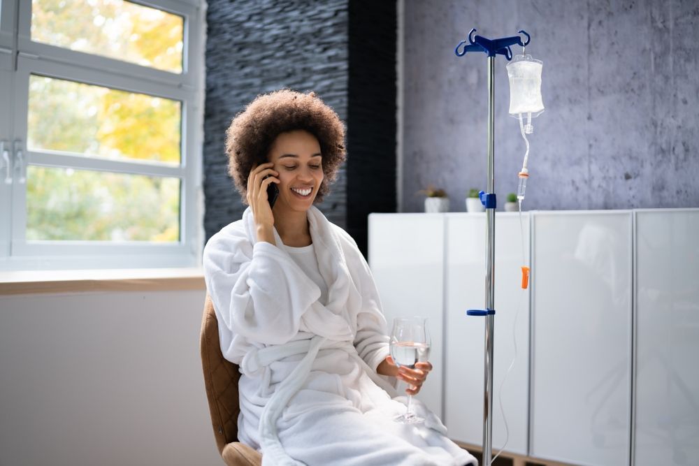 A woman in a bathrobe is sitting in a chair talking on a cell phone.