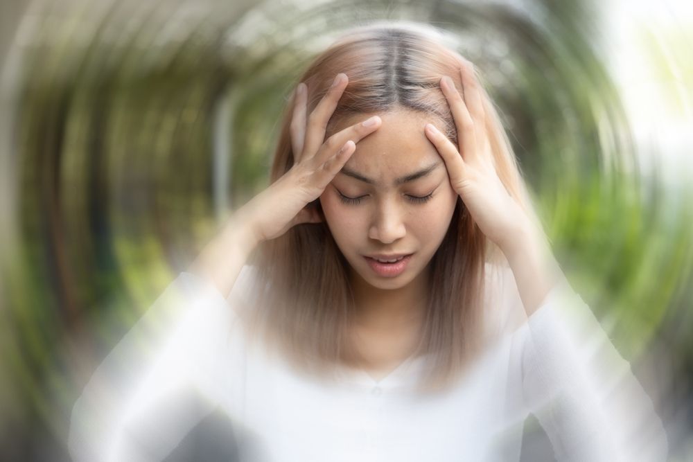 A woman is holding her head in pain because of a headache.