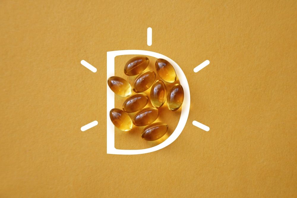 A pile of vitamin d capsules in the shape of a sun on a yellow background.