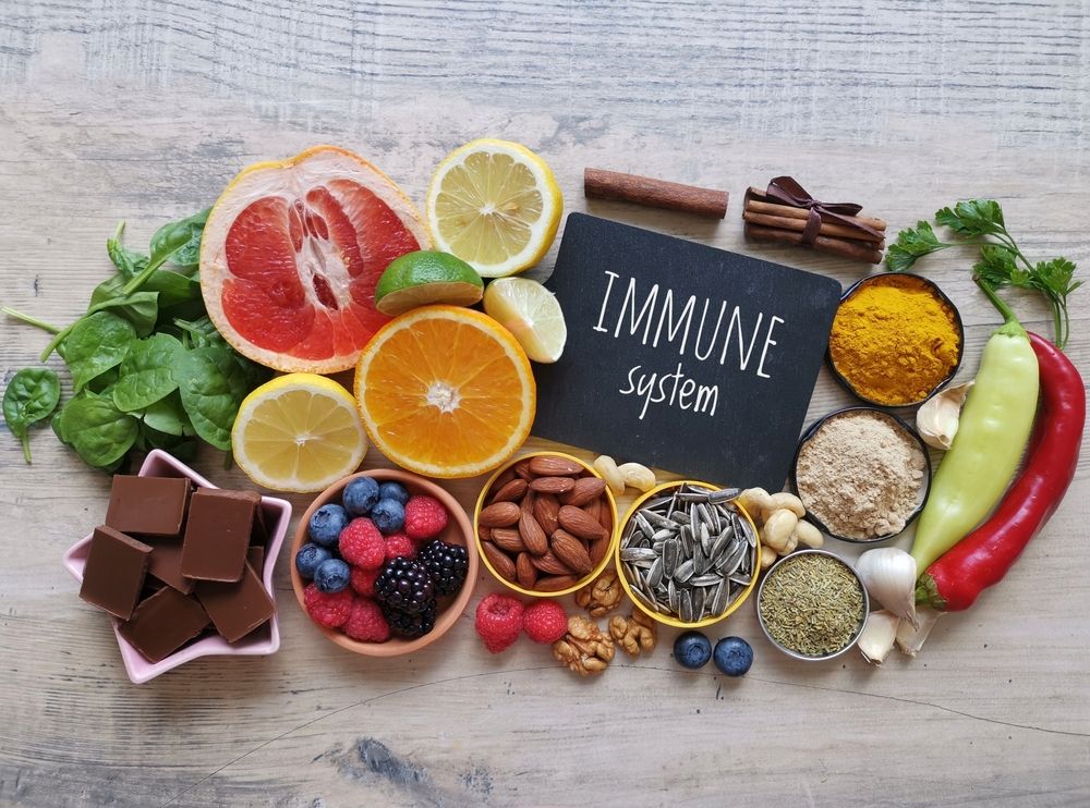 A table topped with fruits , vegetables , nuts , spices and a sign that says immune system.