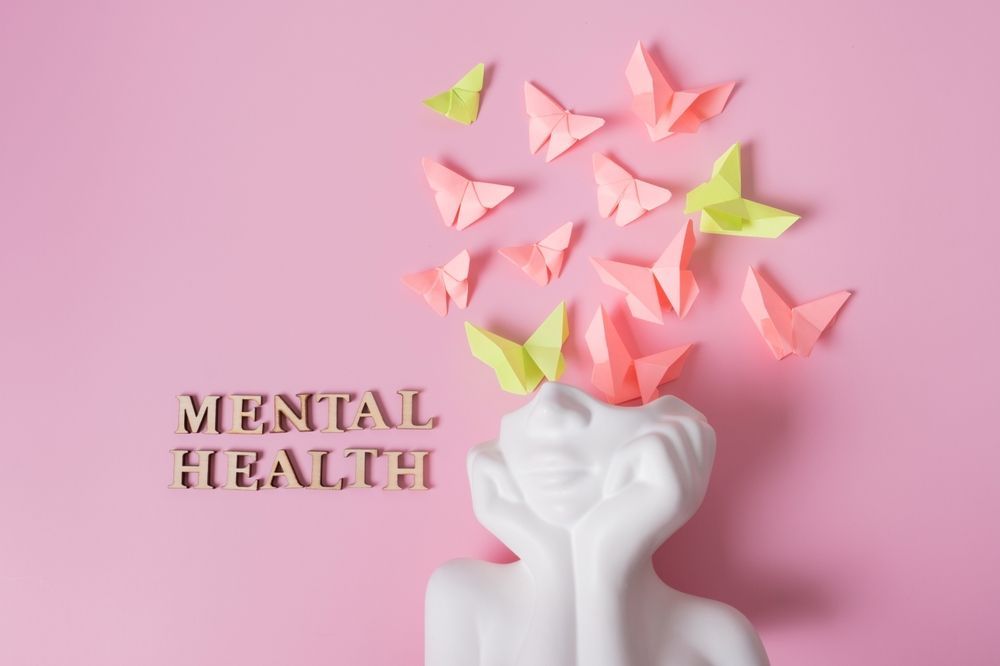 A statue of a woman with origami butterflies coming out of her head on a pink background.