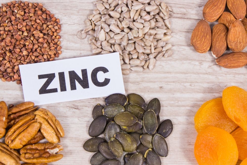 A wooden table topped with nuts , seeds , apricots and a sign that says `` zinc ''.