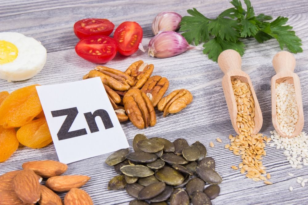 A variety of foods containing zinc are on a wooden table.