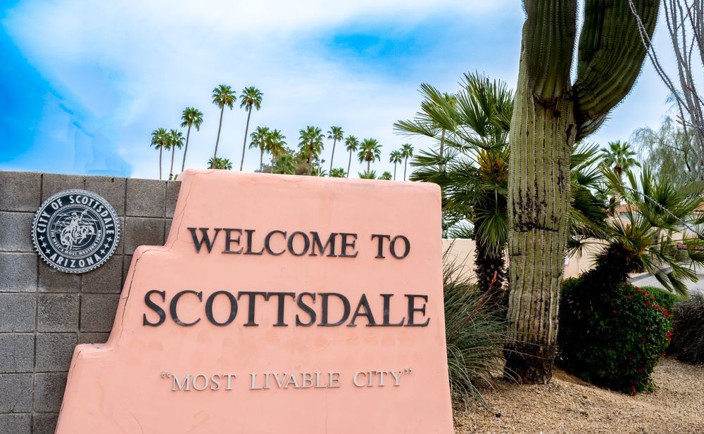 A welcome to scottsdale sign with palm trees in the background