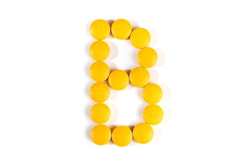 The letter b is made of yellow pills on a white background.