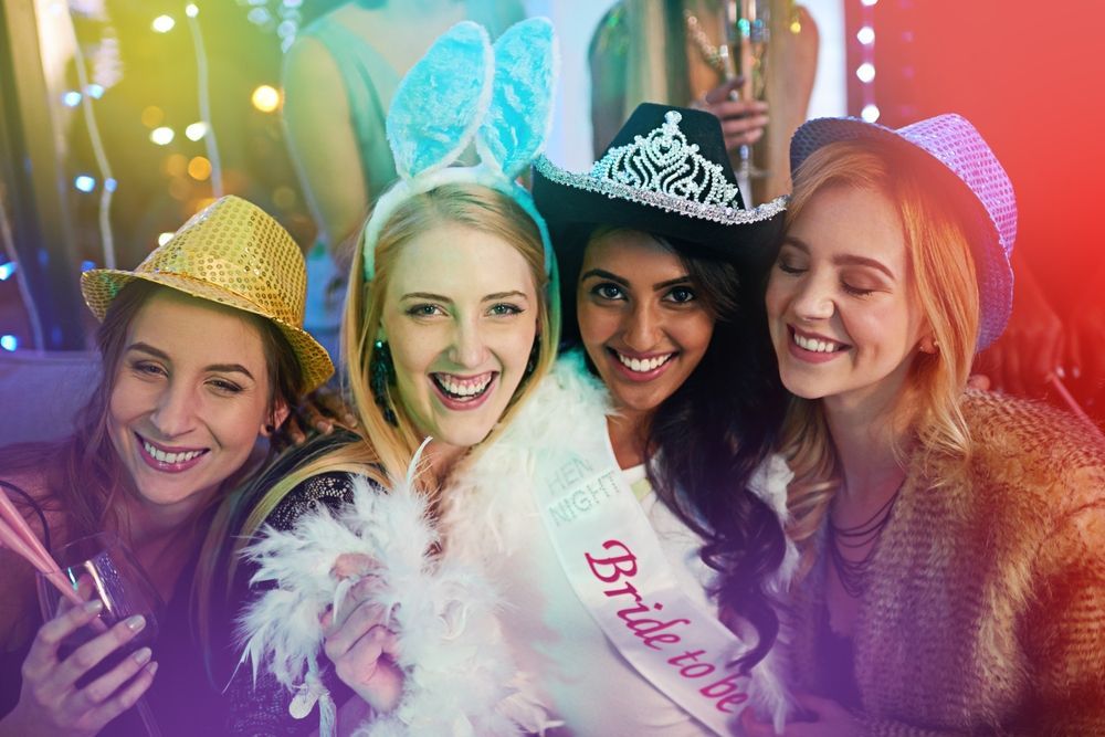 A group of women are posing for a picture at a bachelorette party.