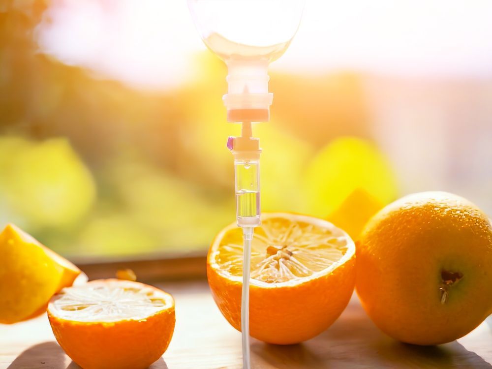 A syringe is sitting on a table next to oranges.