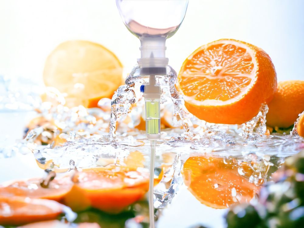 A bottle of liquid is being poured into a glass of orange slices.