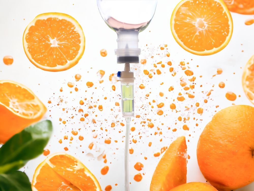 A syringe filled with liquid is surrounded by oranges and leaves.