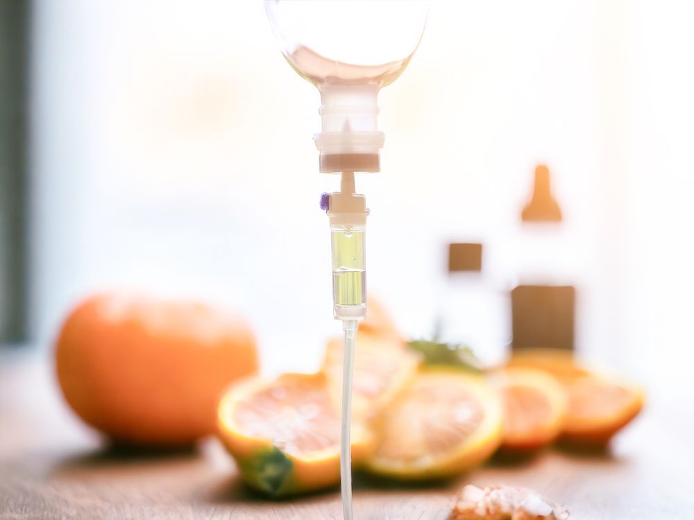 A close up of an intravenous drip with oranges in the background.