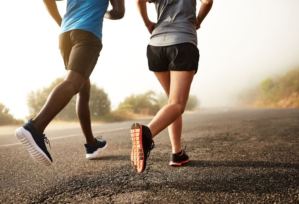 A man and a woman are running down a road.