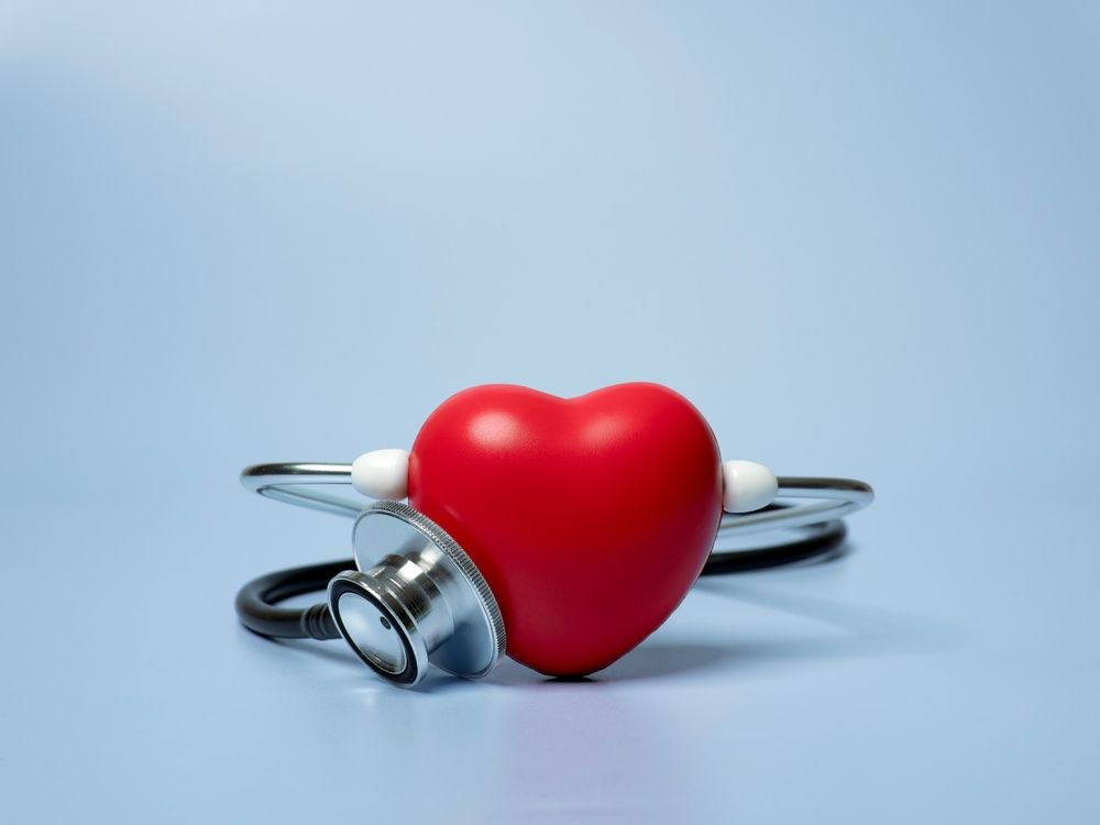 A red heart with a stethoscope around it on a blue background.