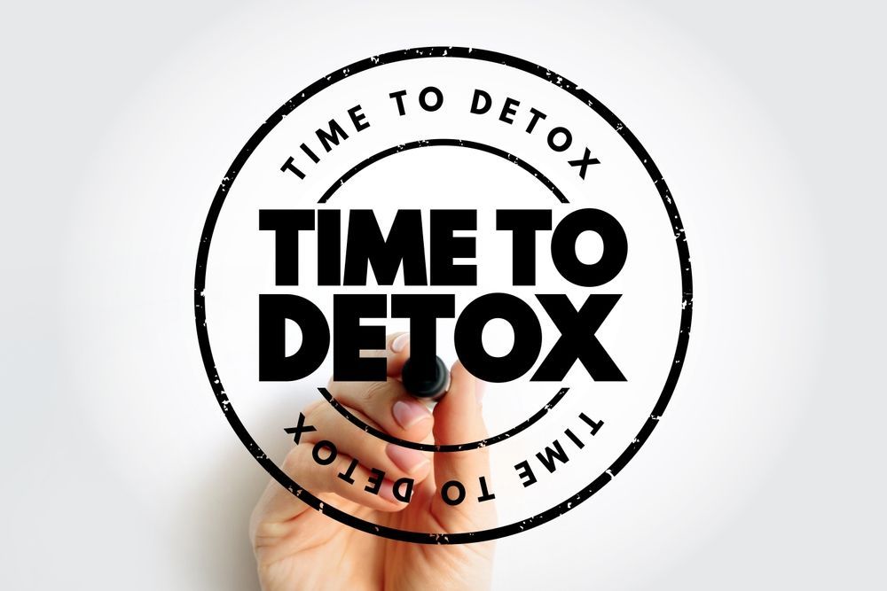 A hand is writing the words time to detox with a marker.