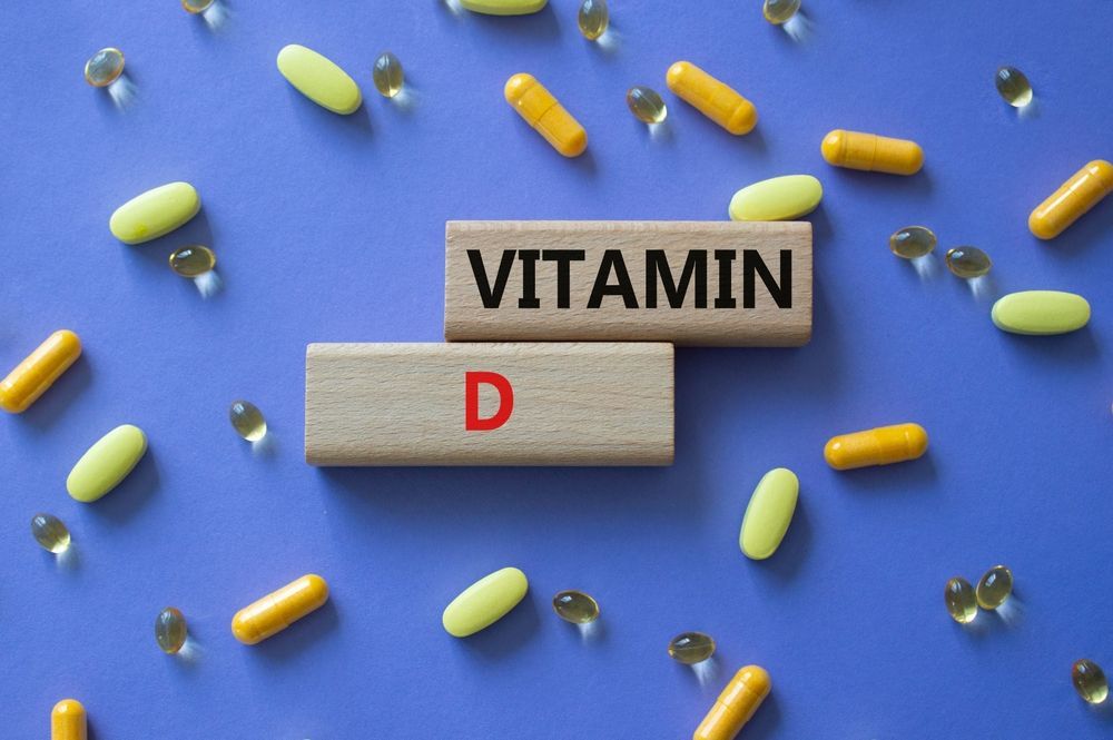 The word vitamin d is written on wooden blocks surrounded by pills and capsules.