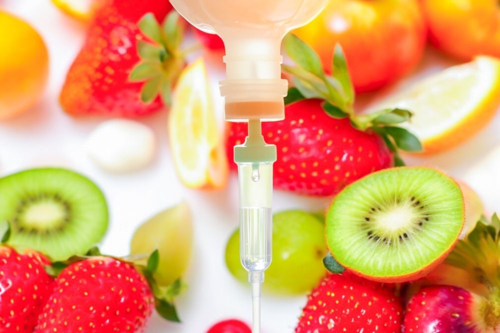 A syringe is being inserted into a bottle of liquid surrounded by fruit.