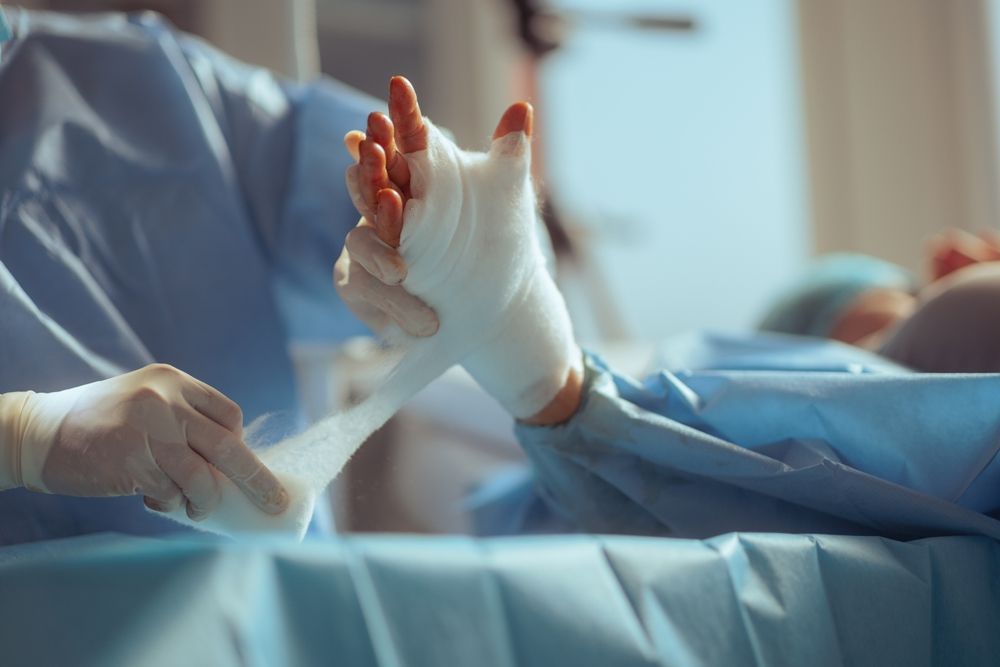 A surgeon is bandaging a patient 's hand in an operating room.