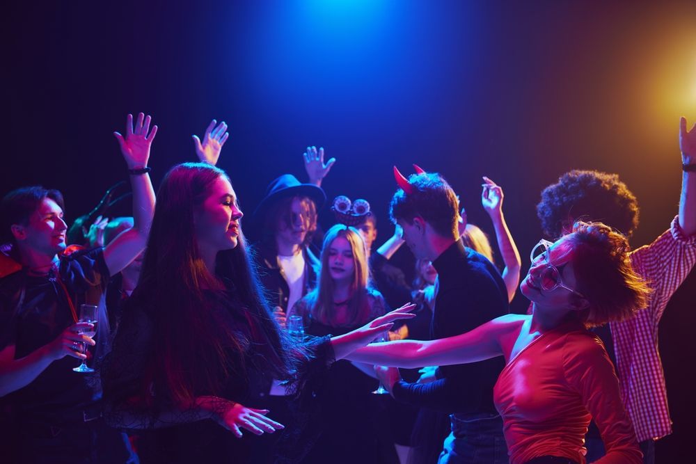 A group of people are dancing in a club with their hands in the air.