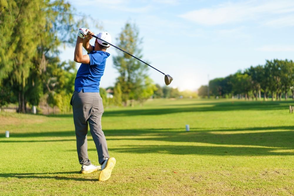 A man is swinging a golf club on a golf course.